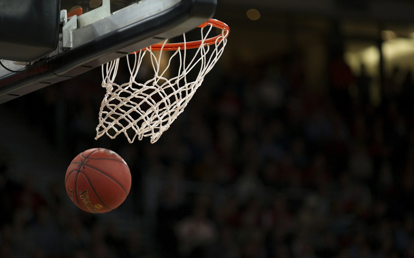 Basketball falling through a hoop during a game