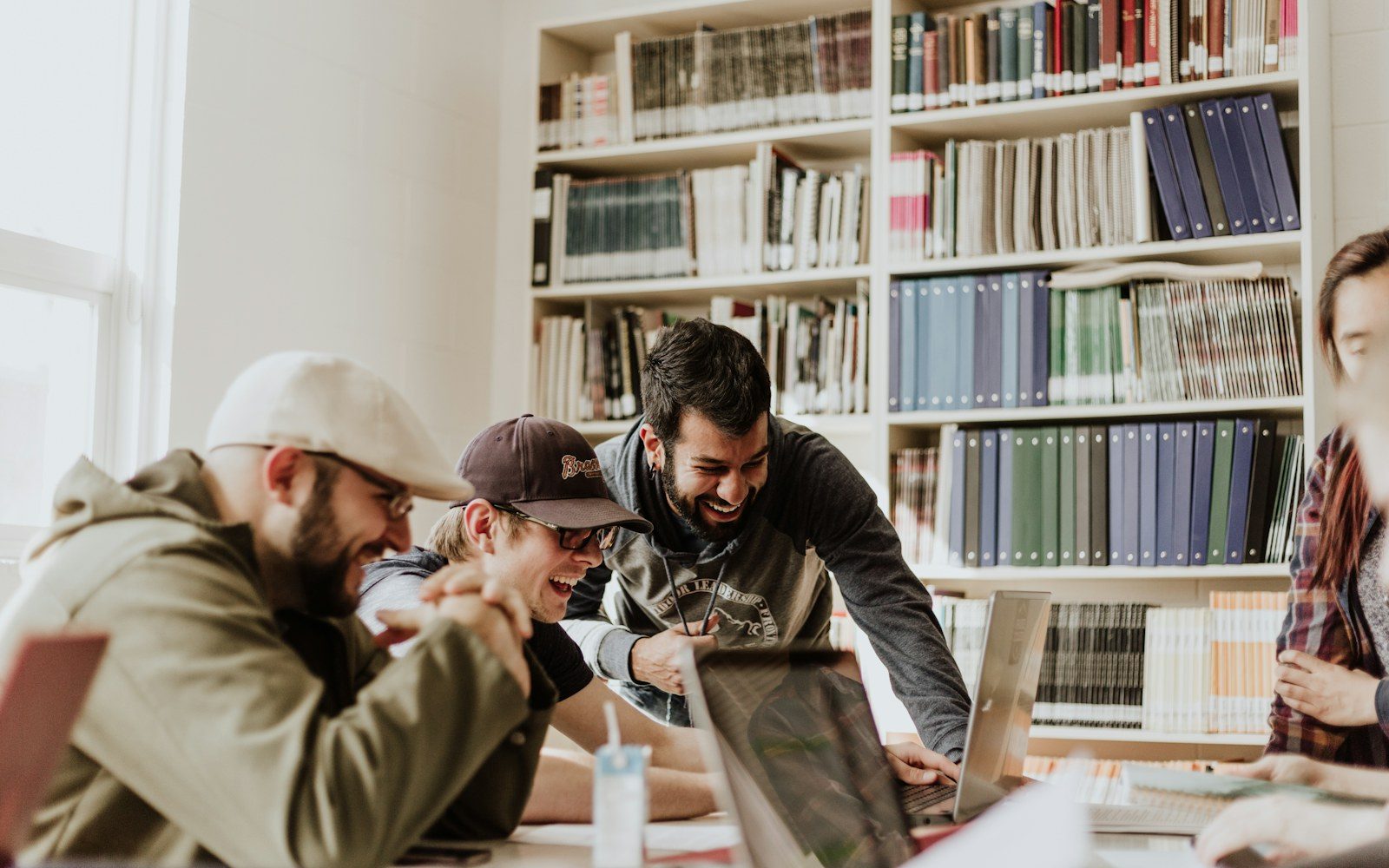 Students studying together in a library with shelves of books behind them