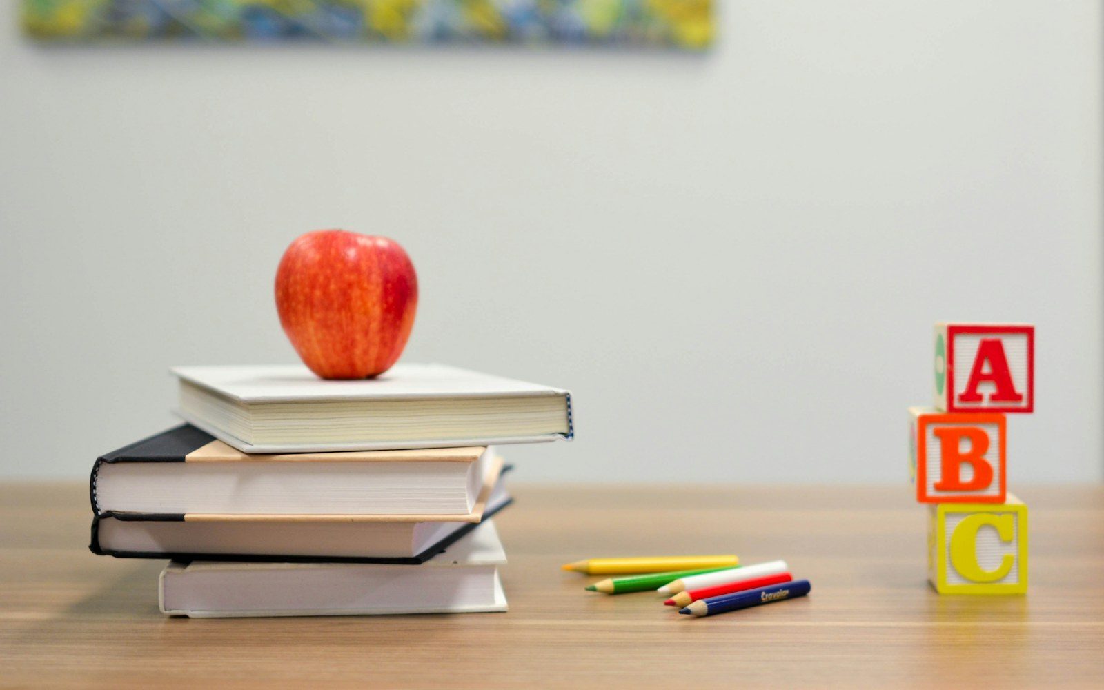 Stack of books with an apple and letter blocks on a study table
